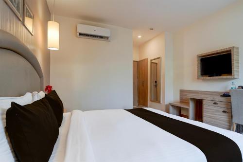 a bedroom with a large white bed with black pillows at Super Townhouse Oak Rajpur Road Dehradun in Dehradun