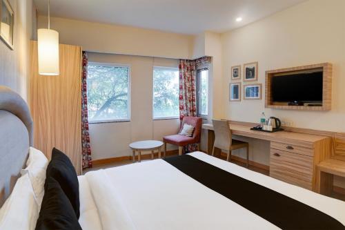 a hotel room with a bed and a desk and a tv at Super Townhouse Oak Rajpur Road Dehradun in Dehradun