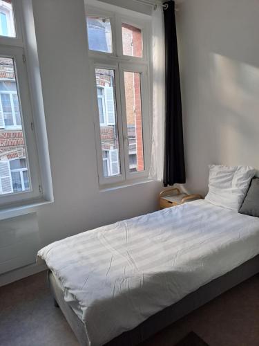 - un lit dans une chambre avec 2 fenêtres dans l'établissement F3 meublé proche gare, à Amiens
