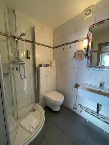 a bathroom with a toilet and a shower and a sink at Hotel Steiger in Schwangau