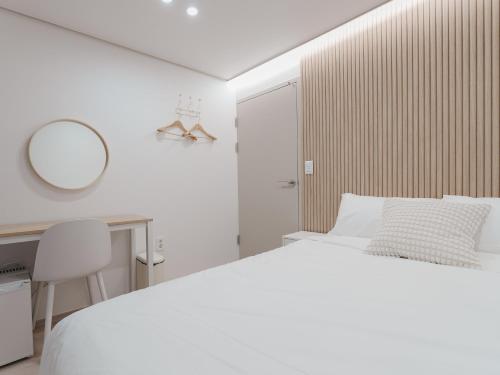 a white bedroom with a bed and a desk and a mirror at Elly stay in Seoul
