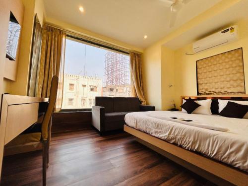a bedroom with a bed and a couch and a window at Golden Square - Kolkata Airport in Kolkata