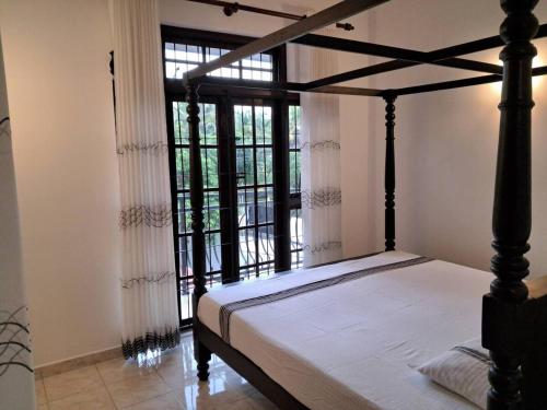 a bedroom with a bed and a large window at Tharan Villa - House in Colombo in Polgasowita