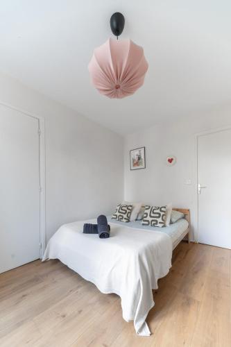 - une chambre blanche avec un lit et une lampe rose dans l'établissement La Grande Maison Clermont - Appartements centre ville, à Clermont-Ferrand