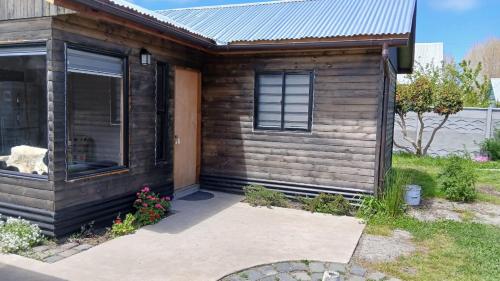 a small wooden house with a door and flowers at Costa Monkul - Carahue y Puerto Saavedra in Nahuentúe