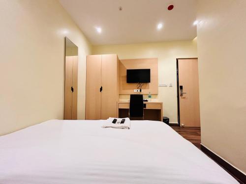 a bedroom with a large white bed and a desk at Golden Square - Kolkata Airport in Kolkata