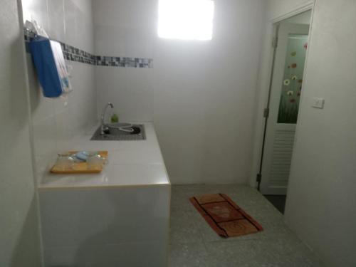 een kleine witte keuken met een wastafel en een spiegel bij Lamai Home 2 in Ko Yao Noi