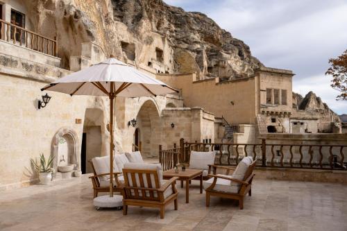 a patio with a table and chairs and an umbrella at Asmalı Konak Cave Suites in Urgup