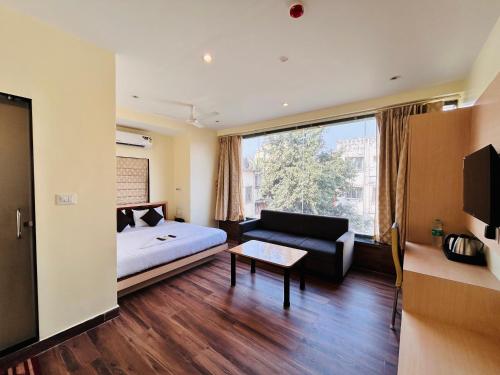 a room with a bed and a couch and a window at Golden Square - Kolkata Airport in Kolkata