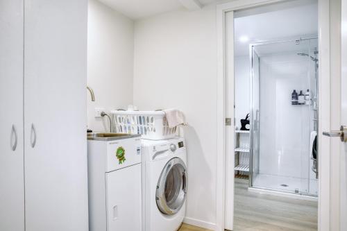 a white washer and dryer in a white laundry room at Classy Modern Unit close to Airport, Shops and Bus in Christchurch