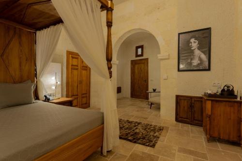 a bedroom with a canopy bed and a bathroom at Asmalı Konak Cave Suites in Urgup