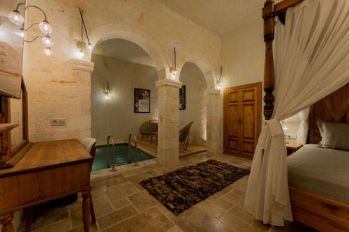 a bedroom with a bed and a tub in a room at Asmalı Konak Cave Suites in Urgup