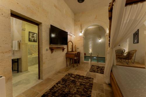 a bathroom with a tub and a television in a room at Asmalı Konak Cave Suites in Urgup