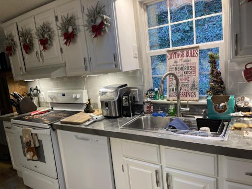 a kitchen with white cabinets and a sink and a stove at Twin Ponds Retreats retreat in Whittier