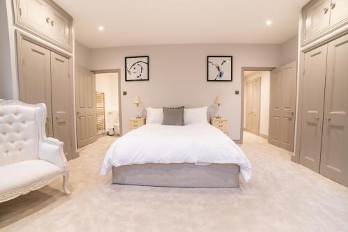 Un dormitorio con una cama blanca y una silla blanca. en The Kings Courtyard Apartment, en Bath