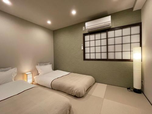 two beds in a room with a window and a window at 悦然民宿-天下茶屋 in Osaka