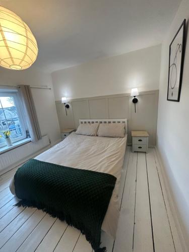 a bedroom with a large bed and a window at Cosy Cottage 7 mins from Cardiff City Center in Cardiff