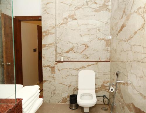 a bathroom with a toilet and a stone wall at The Crescent in Udaipur