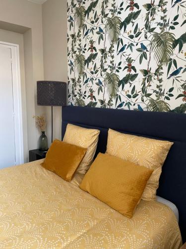 - un lit avec deux oreillers dans une chambre avec papier peint dans l'établissement Studio Belle Époque, à Bailleul