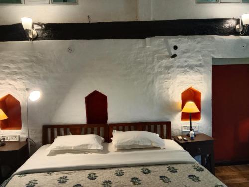 a bedroom with a bed and a wall with two lamps at Labboo'z Café and Lodge in Maheshwar