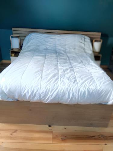 un lit avec une couette blanche et deux tables de nuit dans l'établissement Maison charmante à Écrainville, à Écrainville