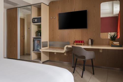 a room with a desk with a television and a chair at Hotel Aria in Rimini