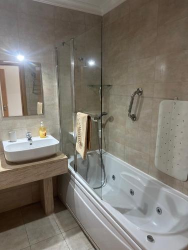ein Badezimmer mit Badewanne, Waschbecken und Dusche in der Unterkunft Jardins da guia in Albufeira