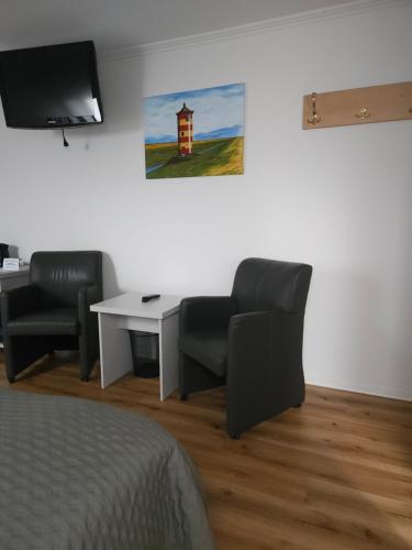 a room with a desk and two chairs and a bed at Hotel Am Deich in Norddeich