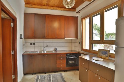a large kitchen with wooden cabinets and a sink at Ontas Traditional Apartment In Gavalochori - BY APOKORONAS VILLAS in Gavalochori