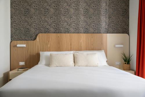 a bedroom with a large white bed with a wooden headboard at Hotel Aria in Rimini