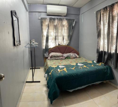 a bedroom with a bed with a green comforter at Pakdin Homestay in Kampong Bukit Katil