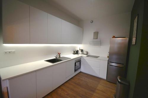 une cuisine avec des armoires blanches et un réfrigérateur en acier inoxydable dans l'établissement Duguesclin - luxueux T3 dans le centre historique, à Montpellier