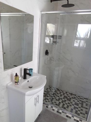 a white bathroom with a shower and a sink at Marina Cottage in Marina Da Gama