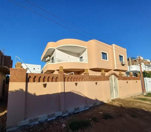 a house behind a brick wall with a fence at Villa Joseph Luxor in Al Aqālitah