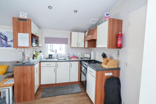 a small kitchen with white cabinets and a stove at Springfield B6 in Brixham