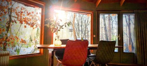a dining room with a table and two windows at Woeste Hoogte - Groesbeek in Groesbeek