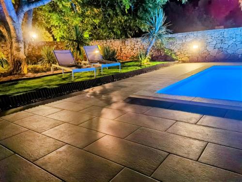 a backyard with a swimming pool and two lounge chairs next to a swimming pool at Jees Exclusive Apartments Hvar in Stari Grad