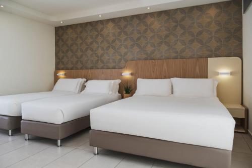 two beds in a hotel room with white sheets at Hotel Aria in Rimini