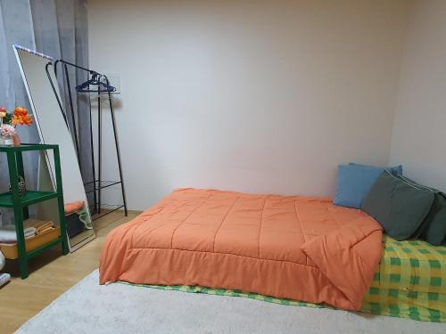 a bedroom with a bed with an orange blanket at Guemho Little House in Daegu