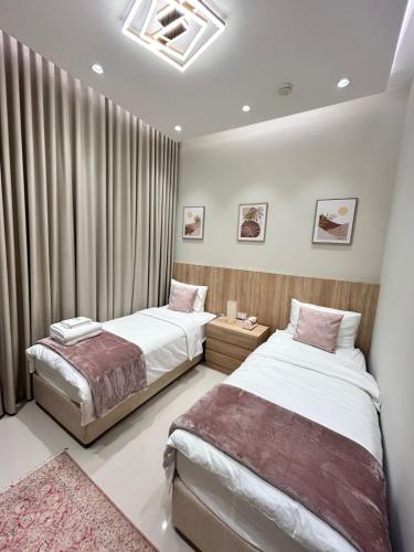 two beds in a bedroom with curtains and a rug at The Riviera Luxury Villa - Seaview Al Dana Fujairah in Fujairah
