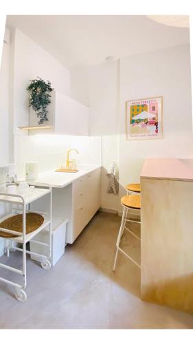 - une cuisine blanche avec un évier et un bureau dans l'établissement Le Petit Henri René, à Montpellier