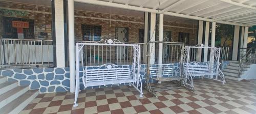 three white benches sitting on the porch of a building at Kulswami Cottage Alibag in Alibaug
