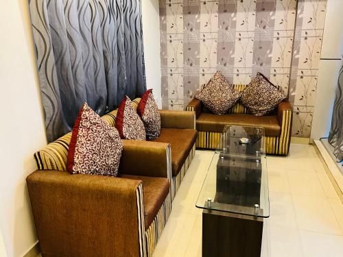 a living room with two couches and a glass table at Hotel Galaxy in Allahābād