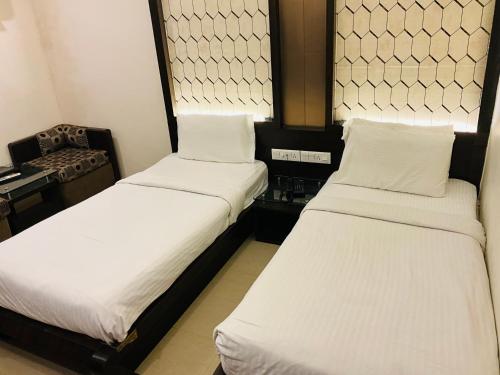 two beds in a small room with a desk at Hotel Galaxy in Allahābād