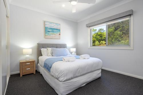 a white bedroom with a bed and a window at Casablanca Luxury Retreat near Shellharbour Marina in Shellharbour