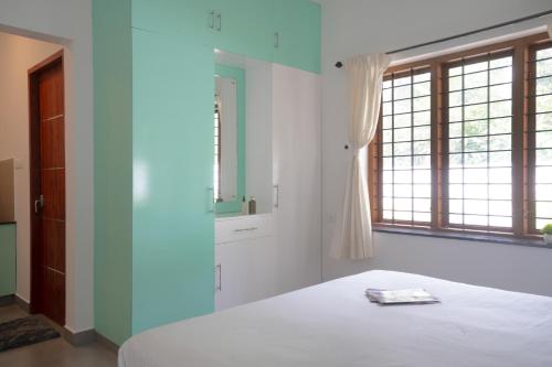a white bedroom with a bed and a window at Elora Plantation Villa By Cluster cloud in Idukki