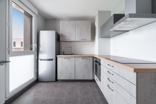  La cuisine est équipée de placards blancs et d'un réfrigérateur. dans l'établissement Le Camélinat - RER C Metro 13, à Gennevilliers