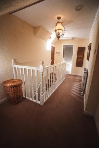 a hallway with a white staircase with a chandelier at 10 Cuddy Point, Scalpay in Scalpay