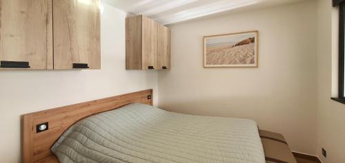 - une petite chambre avec un lit et des placards en bois dans l'établissement La Terrasse sur Houat, à Quiberon