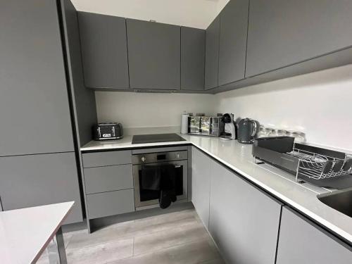 a kitchen with white cabinets and a black oven at Elegant apartment in Milton Keynes